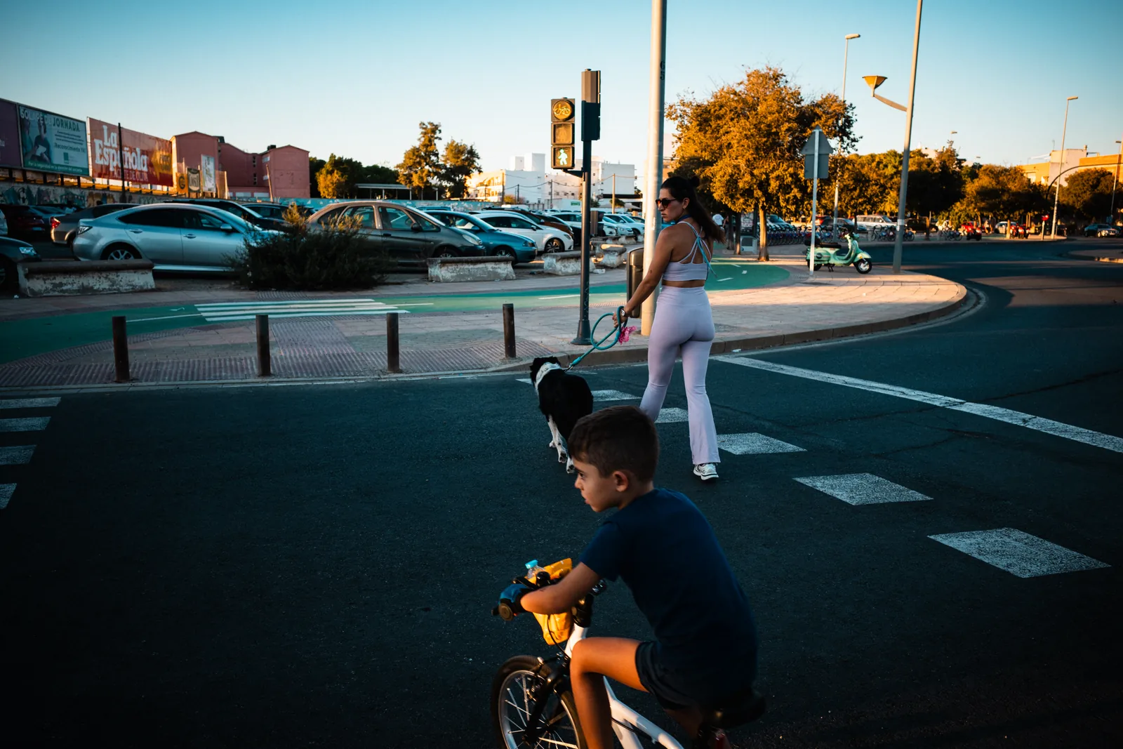 Una bicicleta en primer plano y varios peatones cruzan una calle bajo la luz de la tarde