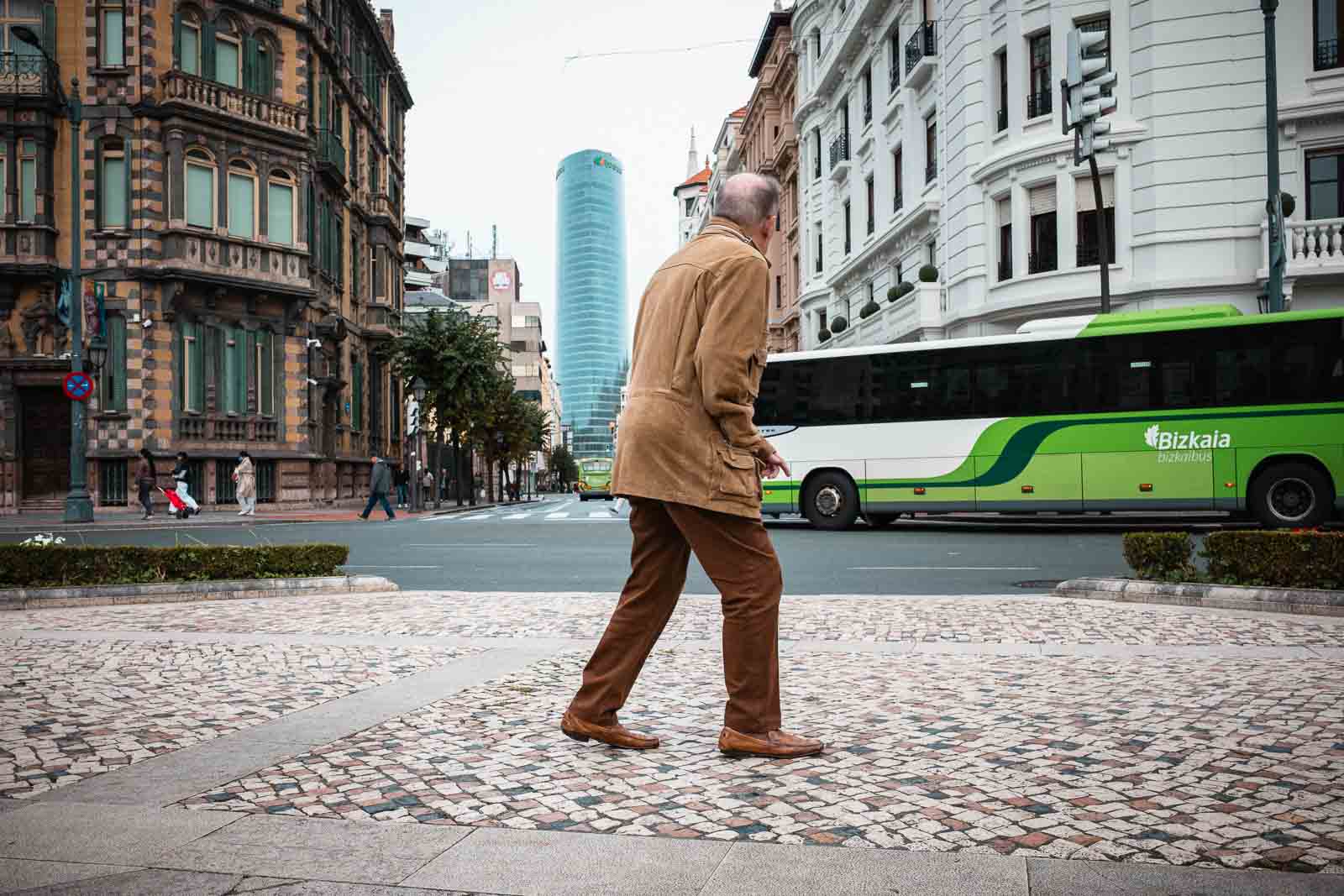 Hombre cruzando una avenida de Bilbao ante un autobús urbano