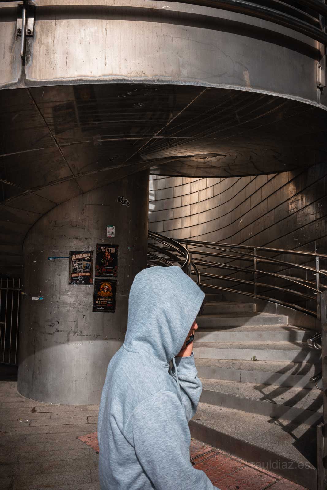 Figura con capucha ante la escalera de acero y hormigón
