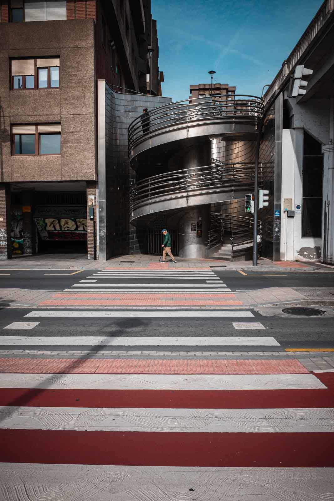 Paso de peatones y pasarela curva en una composición vertical de fotografía callejera en Bilbao